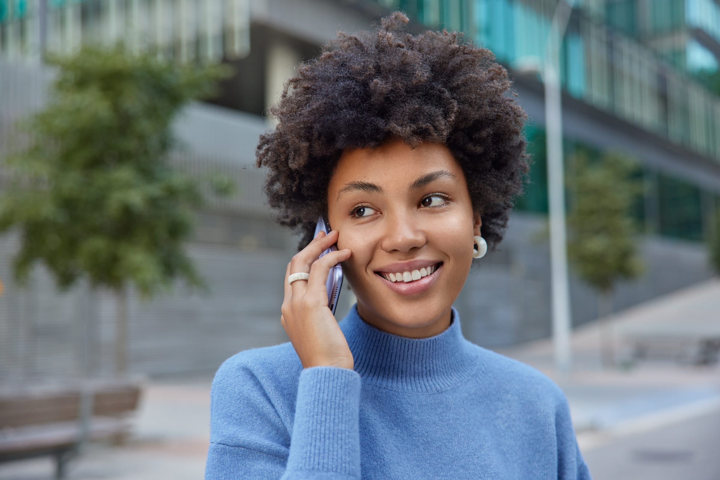 Person smiling while on a phone call outdoors, suggesting friendly contact and conversation.