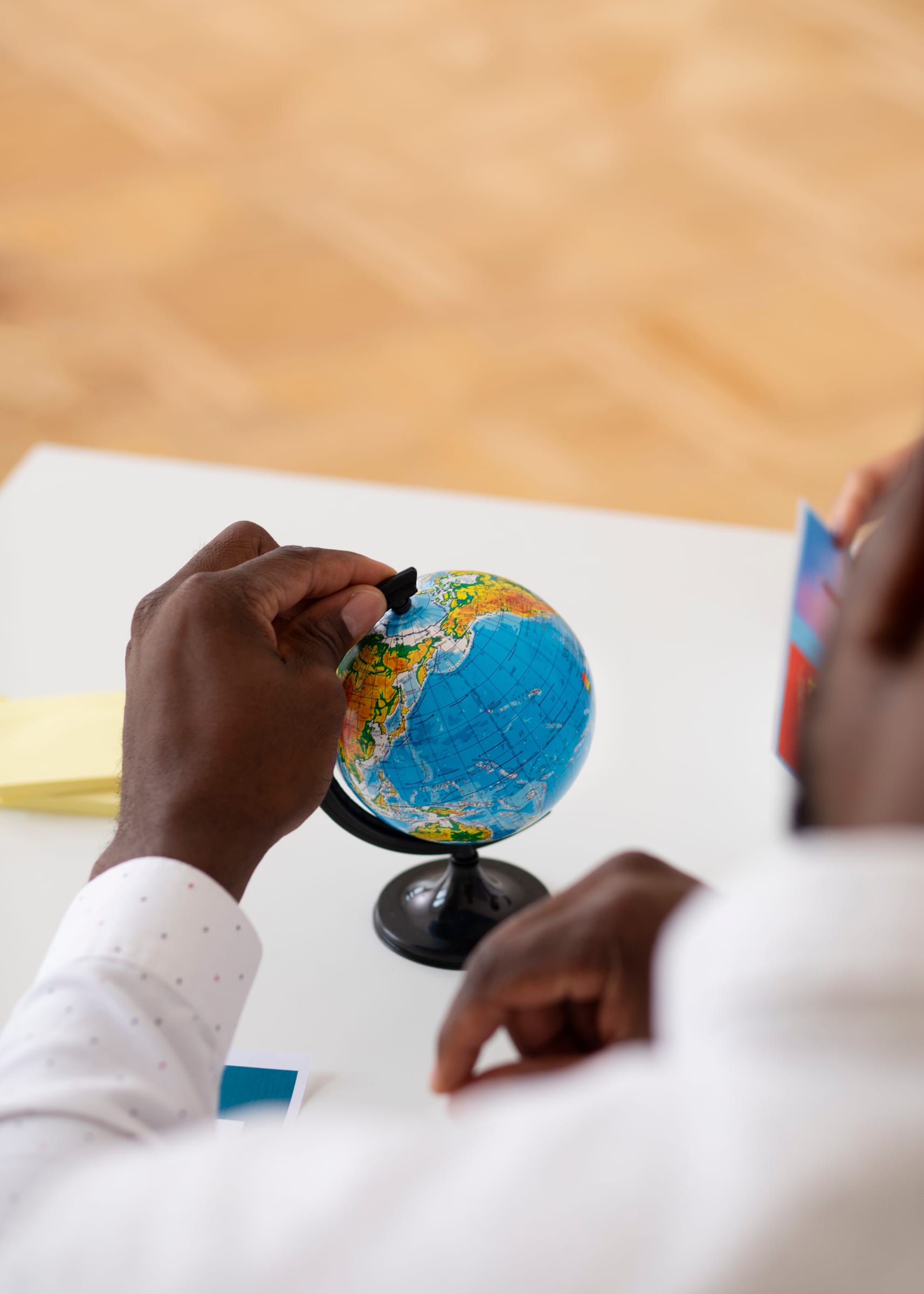Hands at a desk with a small globe, suggesting cross-border collaboration and global dialogue.