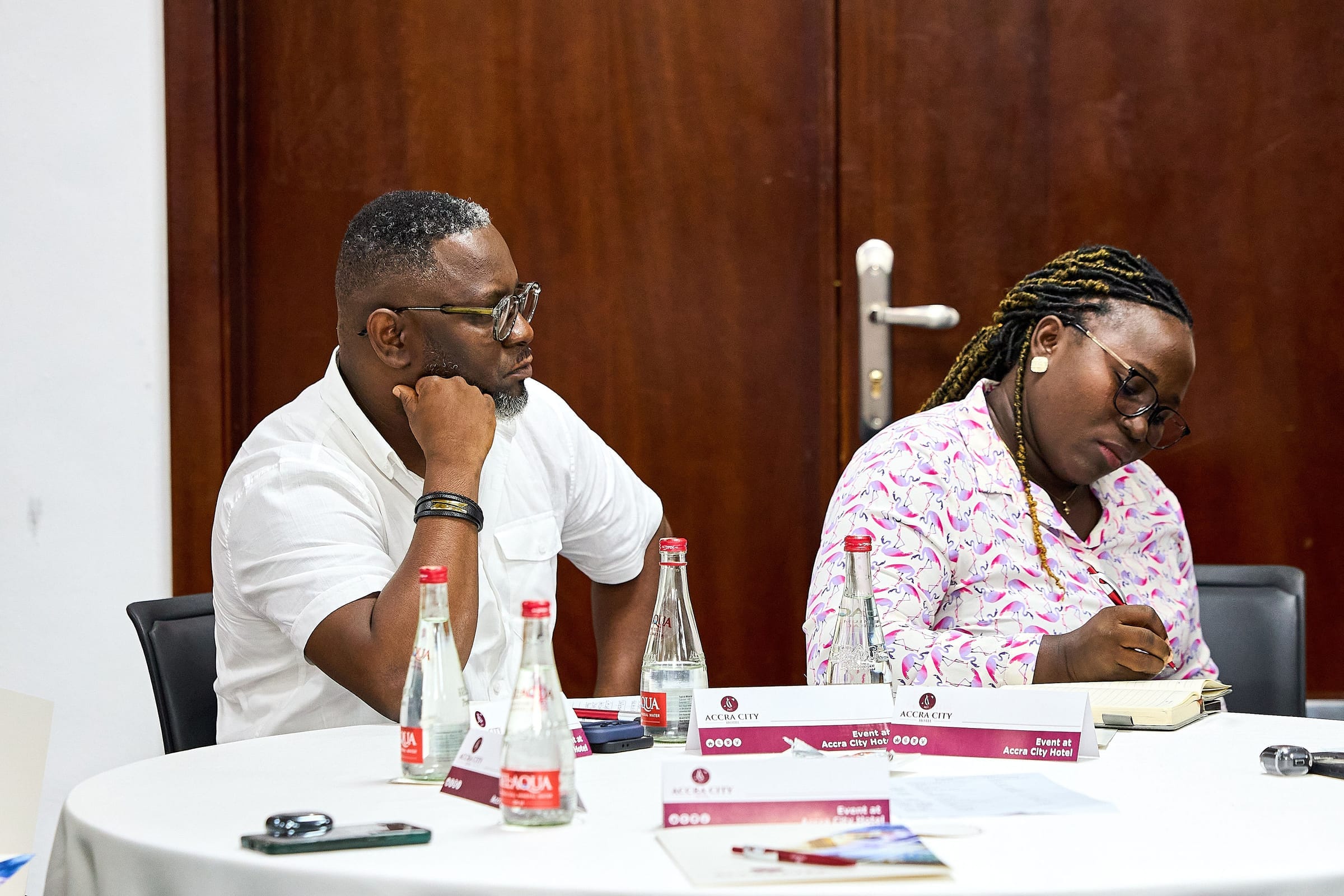 Training and mentorship in a bright indoor space - participants around tables with laptops and discussion, representing structured learning.