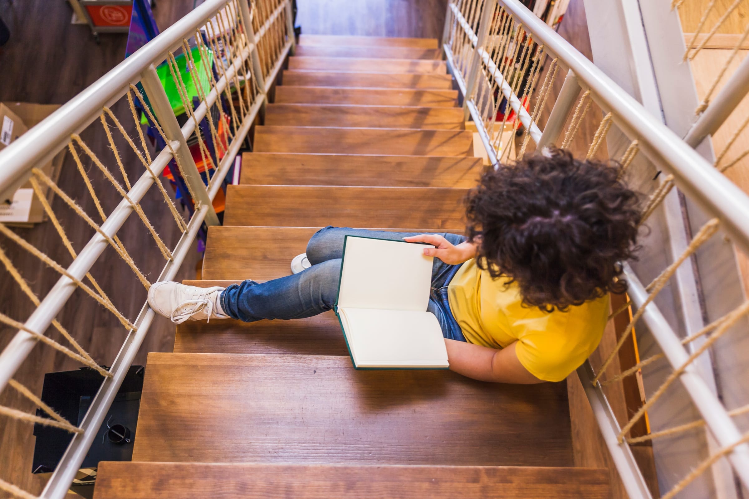 Learner reading on a wooden staircase, symbolizing growth along programs and pathways.